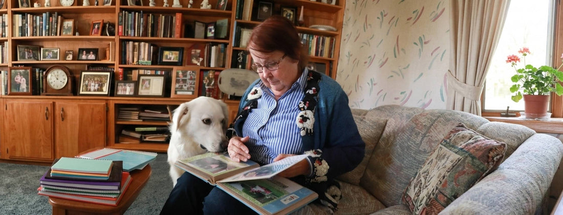 Woman peruses photo album with her dog by her side