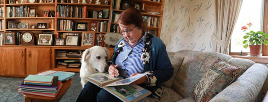 Woman peruses photo album with her dog by her side