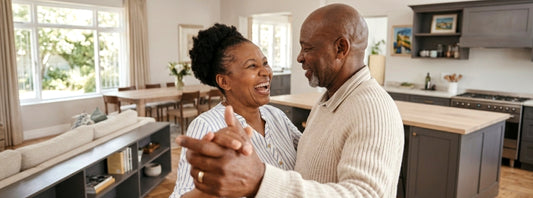 A retirement-age couple dance in their home.