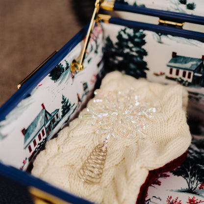 Close-up of a patterned fabric with a house design and a textured white object inside.
