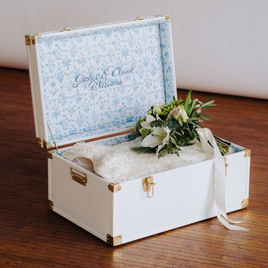 Decorative trunk with floral arrangement and wedding dress inside