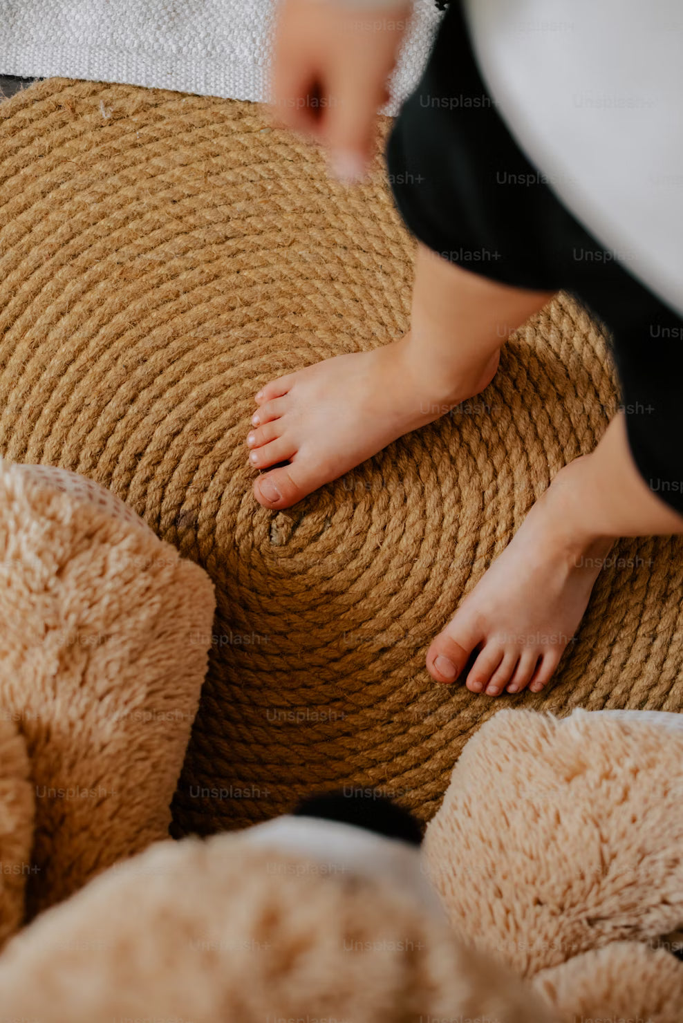 Close-up of a child's feet on a textured brown ottoman with soft beige cushions.