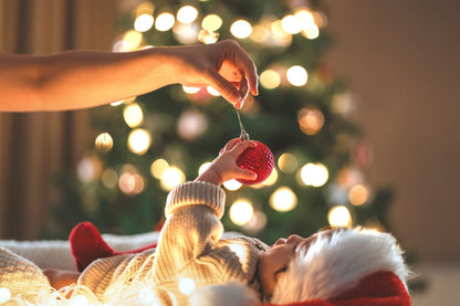 Baby playing with an ornament in front of a Christmas tree